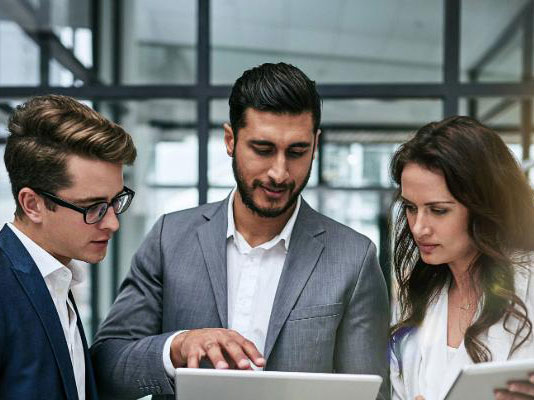 Fotografía personas mirando una tablet en la oficina.